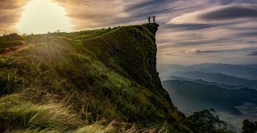 two people stretch on top of a mountain