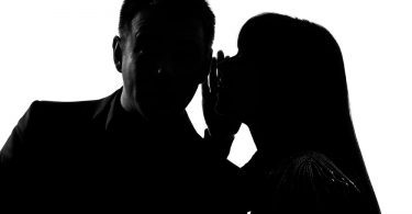 couple hidden in shadows and woman is telling man a secret