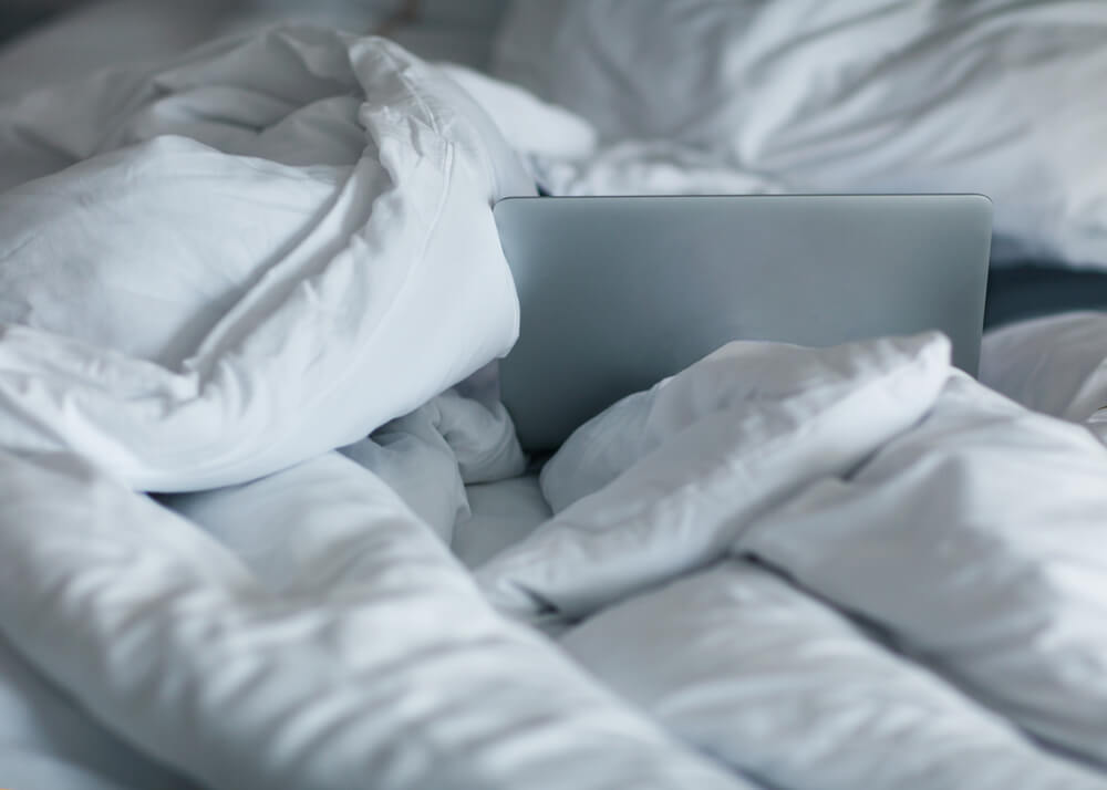 an unmade bed with a laptop in it, but no masturbation