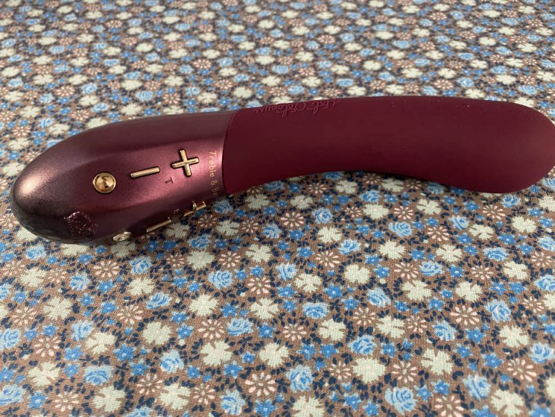 unboxed Kurve lying on its side on multi-colored fabric - blog banner image for Kurve sex toy review