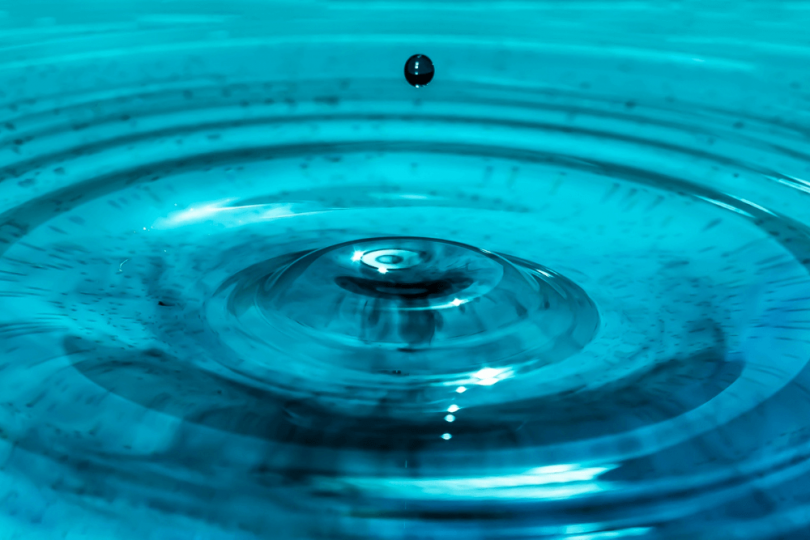 water droplet creating ripples in blue water as a concept for meditation