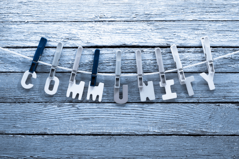 blog banner with the letters spelling out community hung on a line with plastic clothespins in a gray scale image as a concept for finding your kinky community