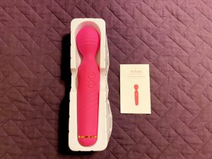 Sucking Clitoral Stimulator and Wand Massager by Sohimi in packaging next to instruction manual on top of purple bedspread
